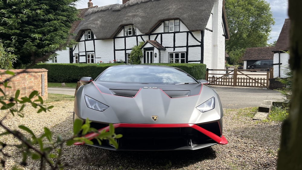 Une voiture de sport argentée garée devant une maison