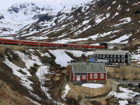 a red train traveling down tracks next to a snow covered mountain