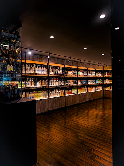 A dimly lit, elegant tasting room with dark wood shelves filled with premium rum bottles.