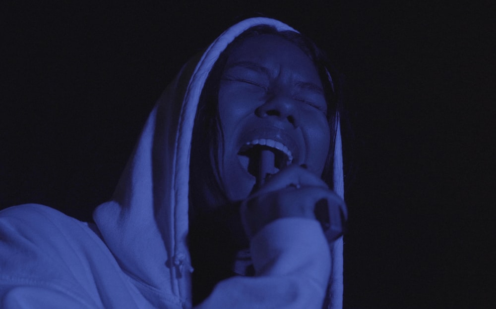 a woman in a hooded jacket singing into a microphone