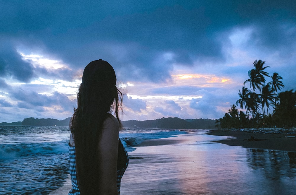 a woman standing on a beach next to the ocean