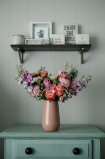 a pink vase filled with lots of flowers on top of a table