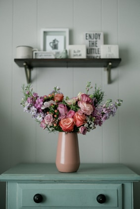 a pink vase filled with lots of flowers on top of a table