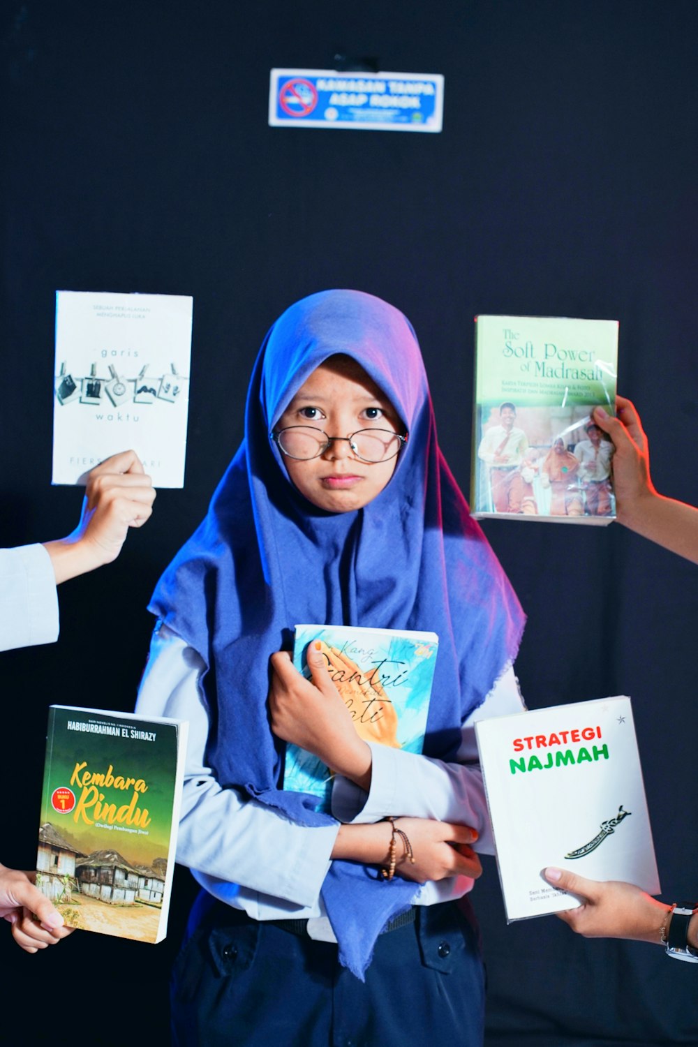 a woman in a blue hijab holding books