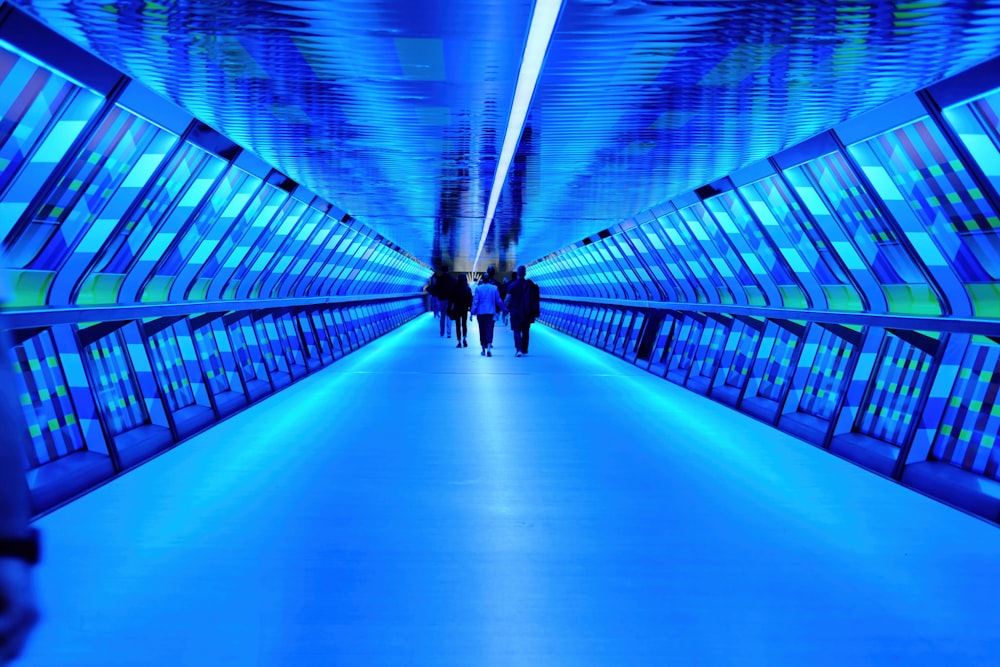 two people are walking down a blue walkway