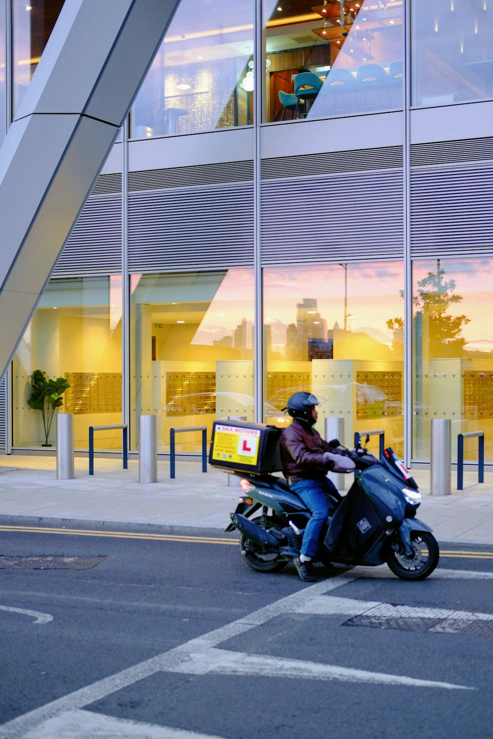 a man riding a motorcycle down a street next to a tall building