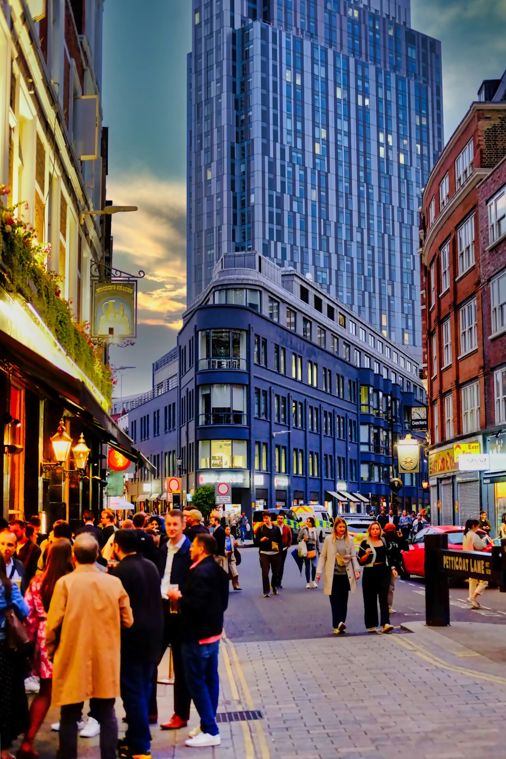 a group of people walking down a street next to tall buildings