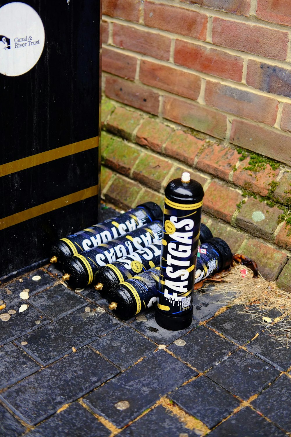 a couple of bottles sitting on the ground next to a brick wall