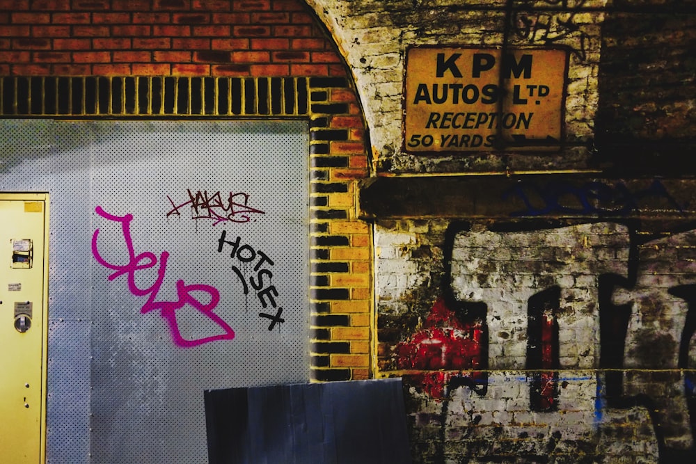 a door with graffiti on it next to a brick wall