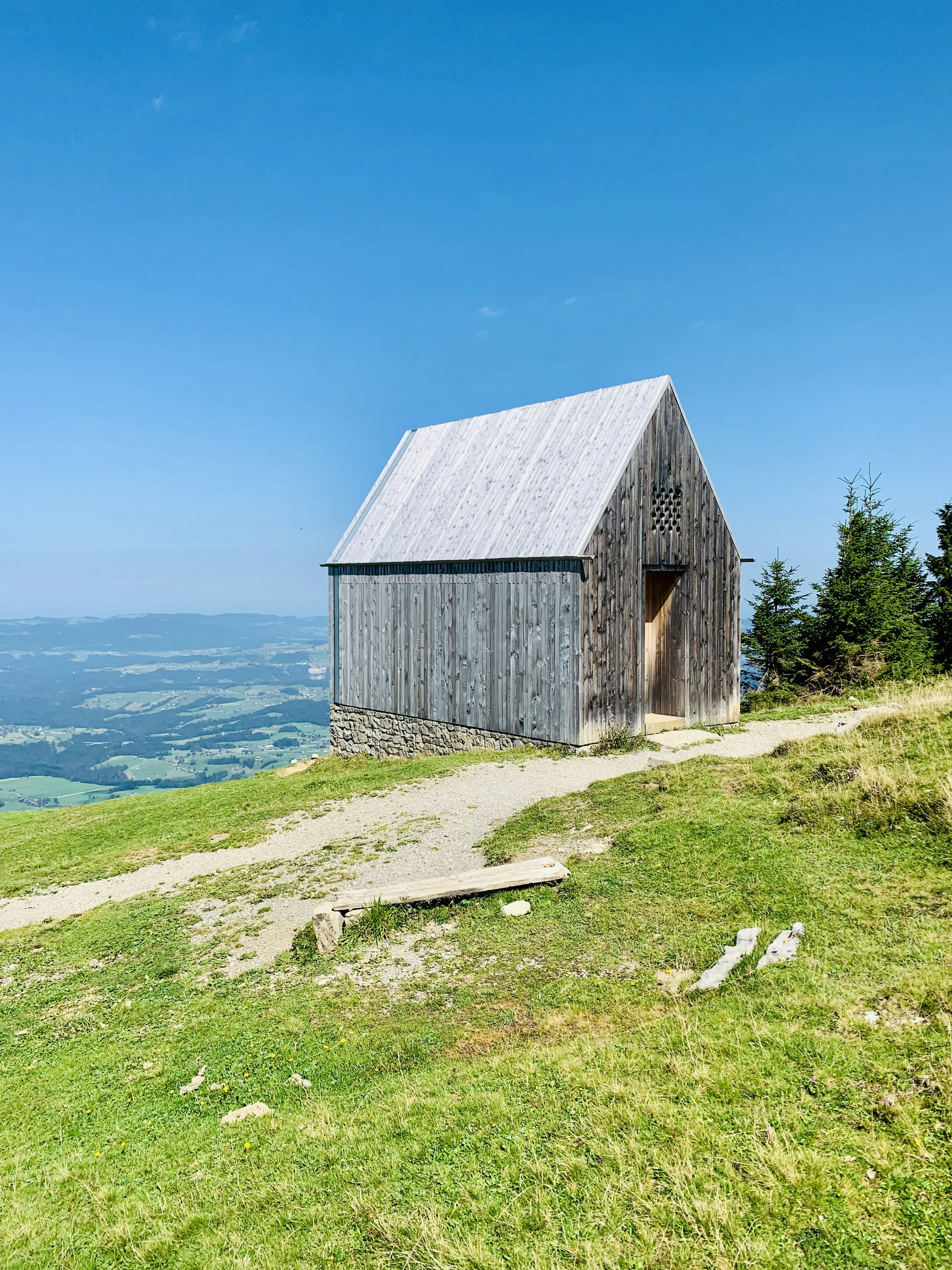 a wooden building sitting on top of a lush green hillside