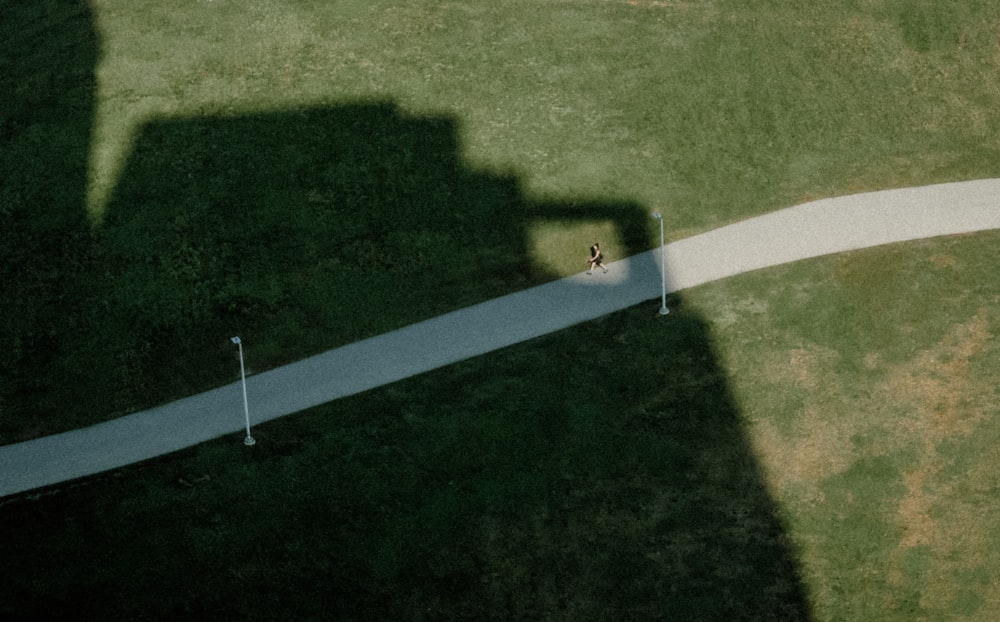 a shadow of a person walking down a road