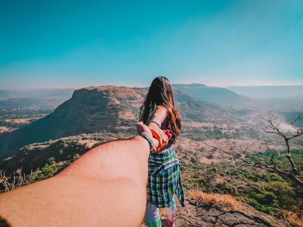 a person holding the hand of another person on top of a mountain