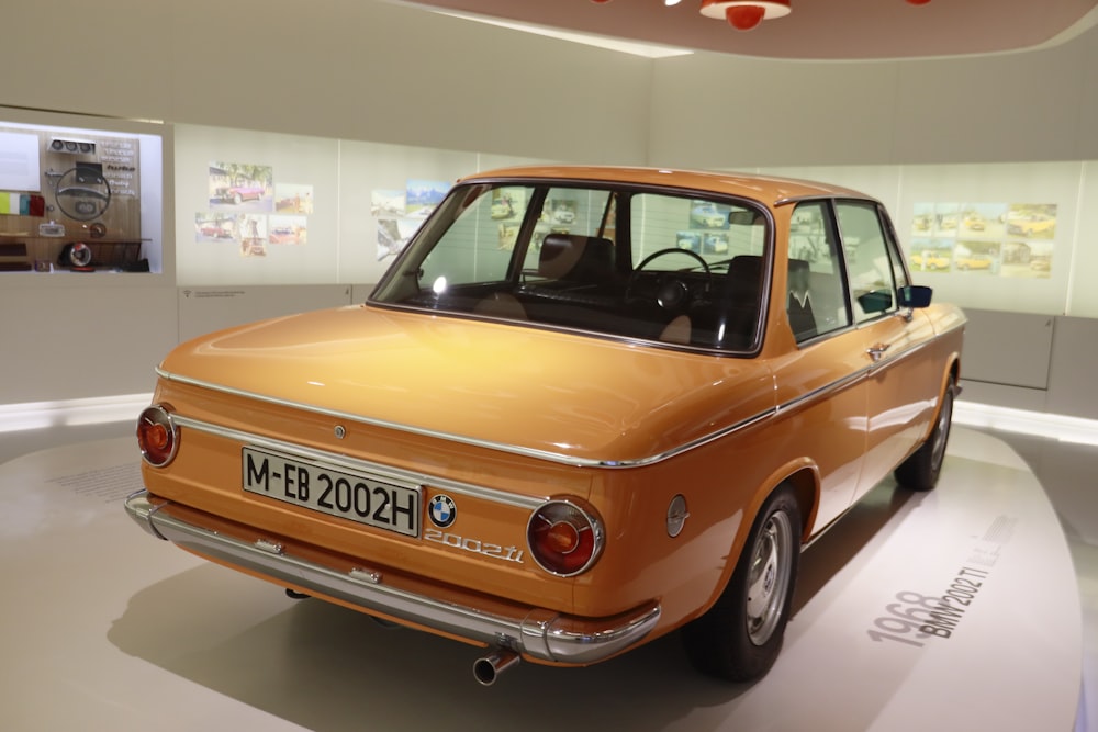 an orange car is on display in a museum