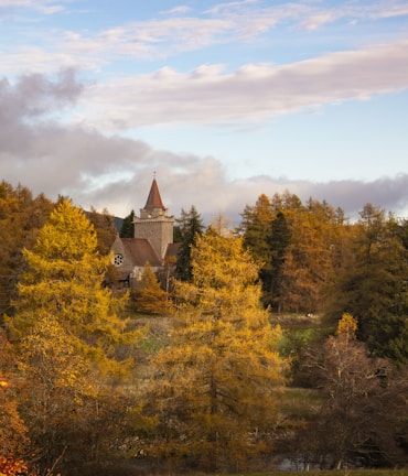 A peaceful countryside church surrounded by autumn trees at sunset.