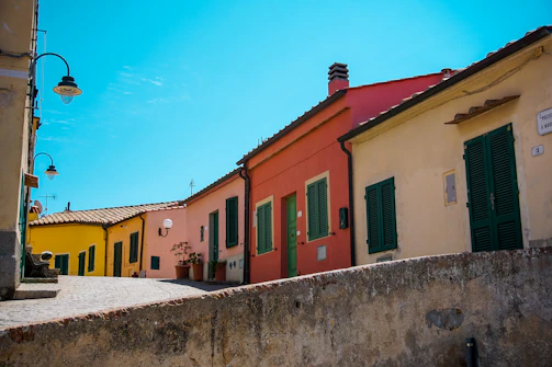 A lively village street with traditional houses painted in warm hues and locals enjoying a sunny day.