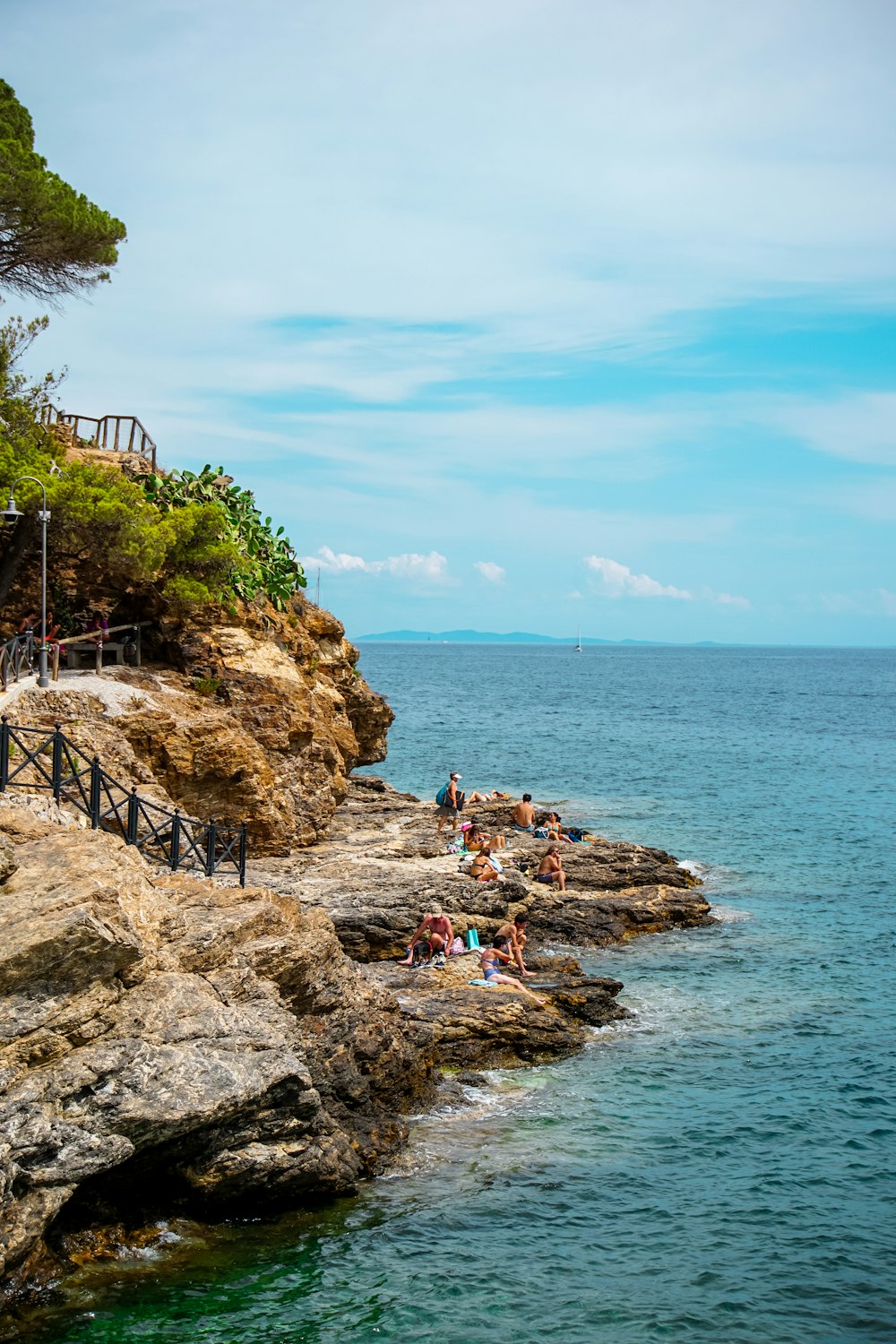 a group of people sitting on top of a cliff next to the ocean