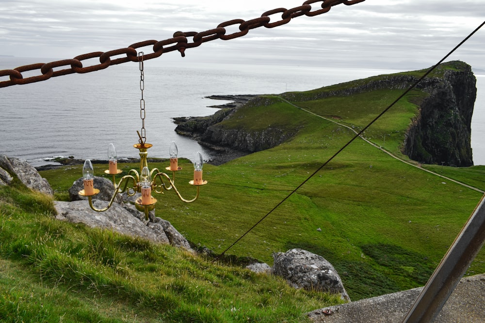 a chandelier hanging from a chain in front of the ocean