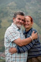 A warm scene of a smiling senior couple wrapped in cozy scarves with the Canadian flag and snowy mountains in the background.