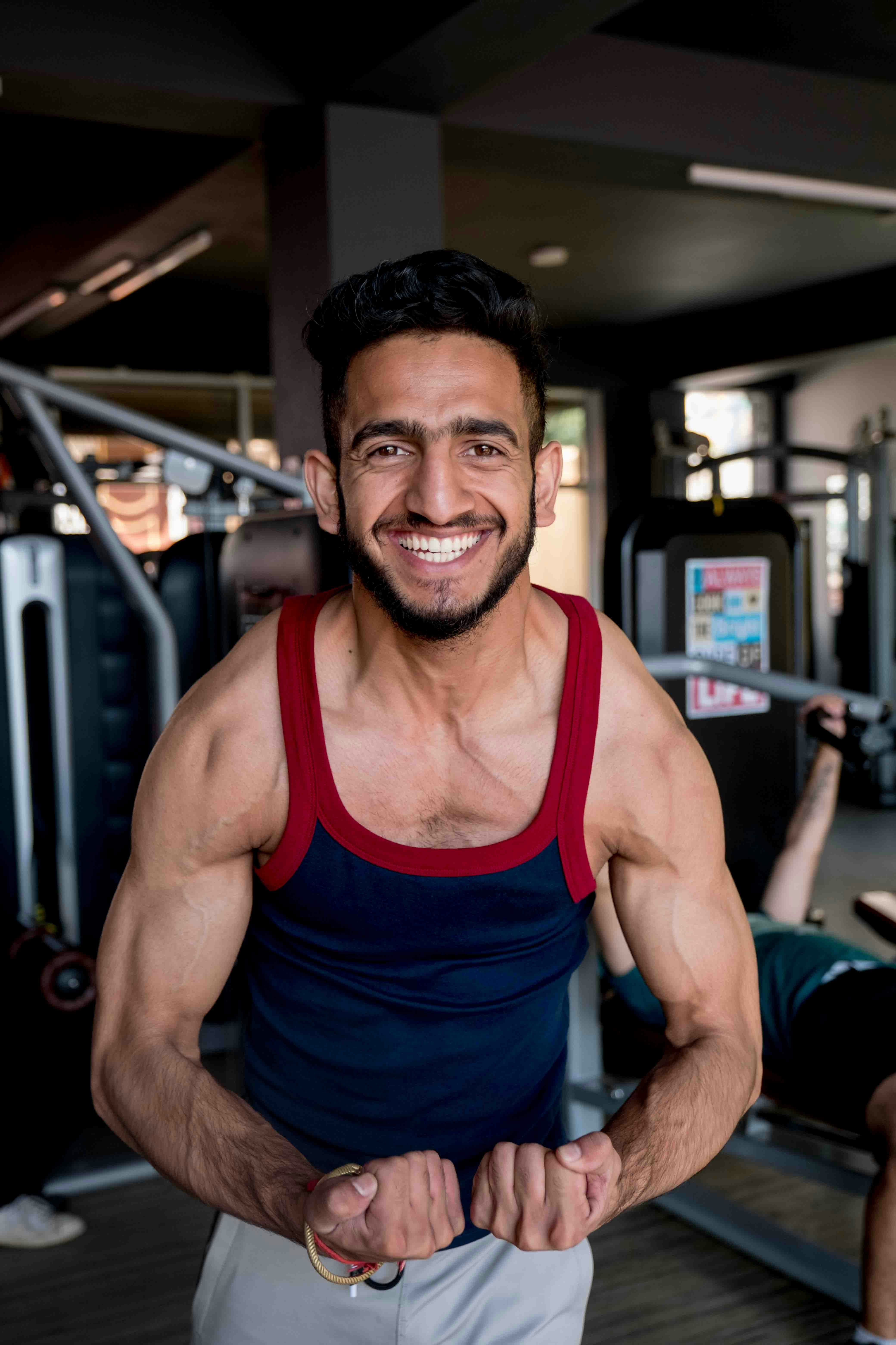 Athletic man flexing, proud after muscle gain transformation, gym backdrop