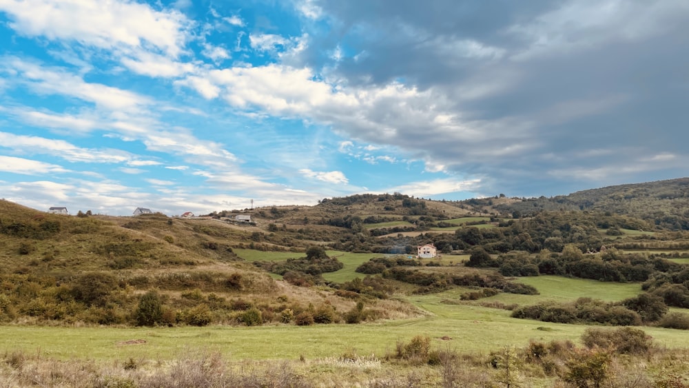 a grassy field with a house on a hill in the distance