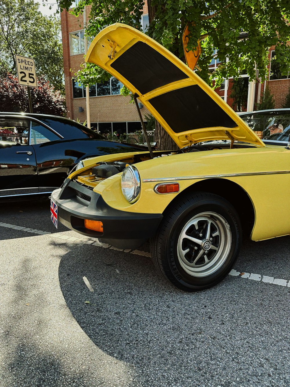a yellow car with its hood open in a parking lot