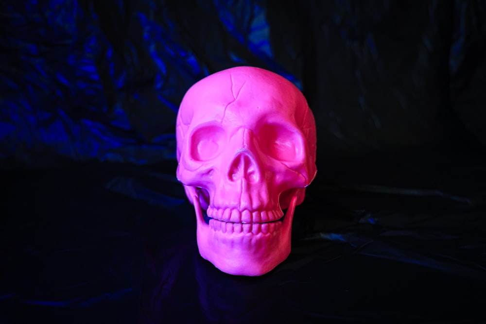 un crâne rose assis sur une table noire