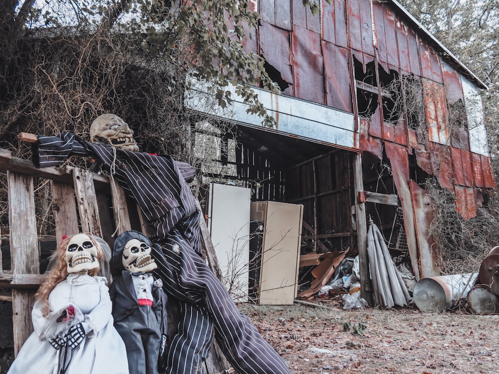 a couple of creepy dolls standing in front of a barn