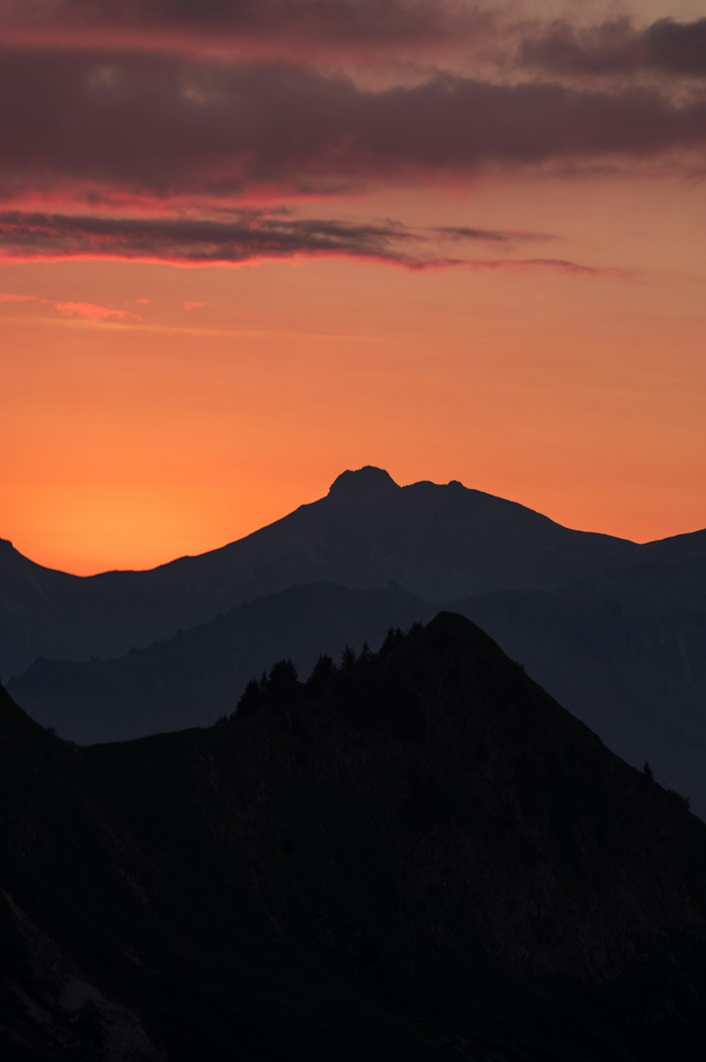 the sun is setting over a mountain range