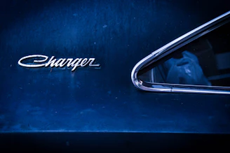 Close-up of a black Dodge Charger emblem shining under neon lights.
