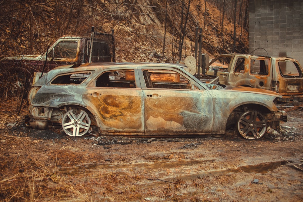 a rusted out car sitting in the middle of a field