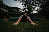 A person stretching outdoors in the morning sunlight, surrounded by greenery