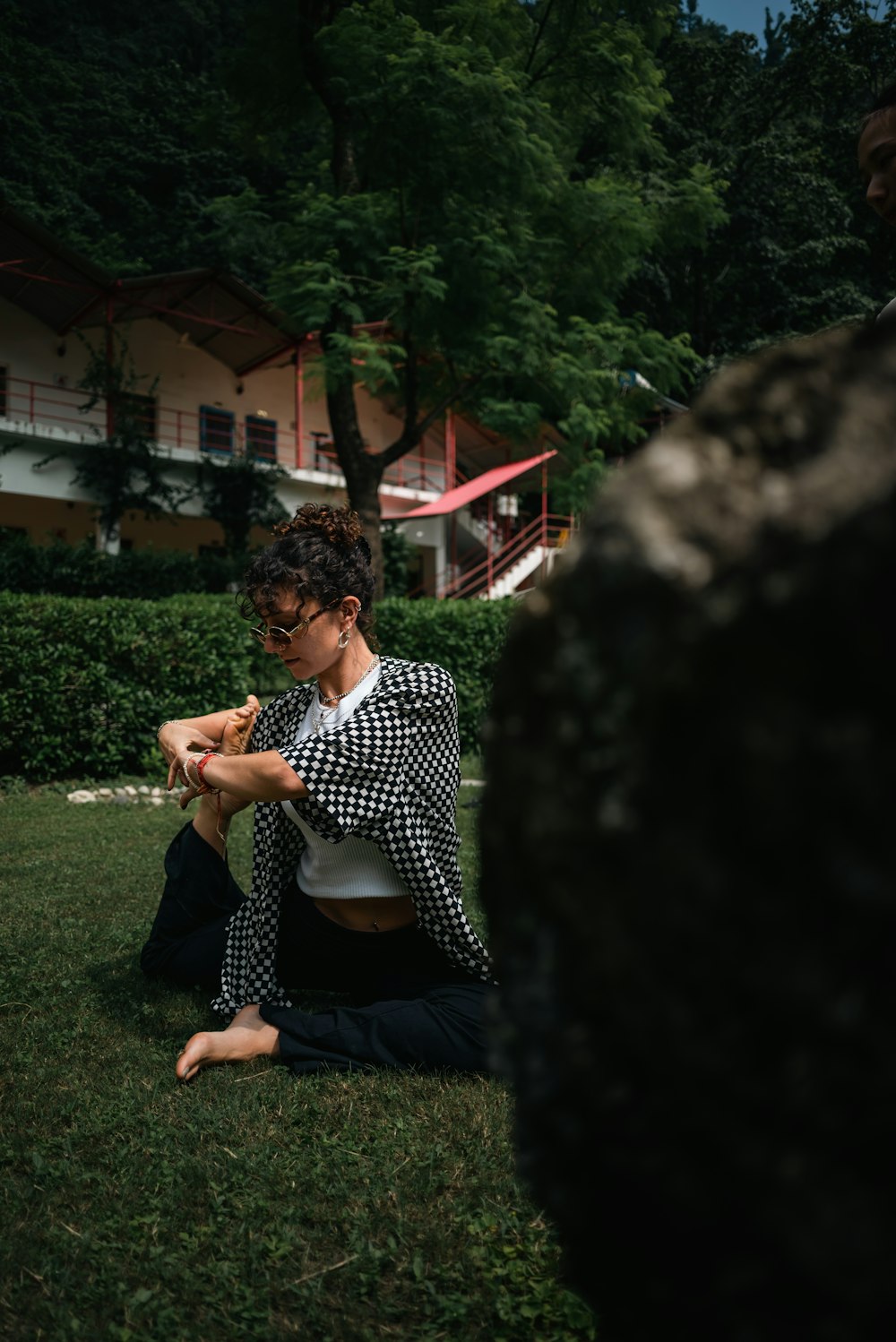 a woman sitting on the ground in a yard