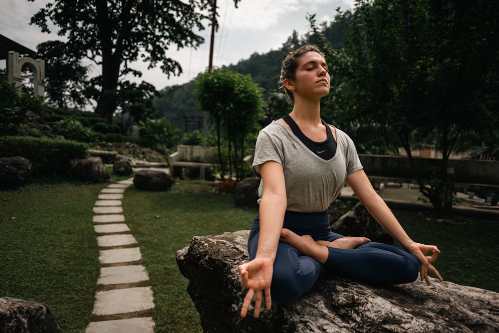 a woman sitting on a rock doing yoga