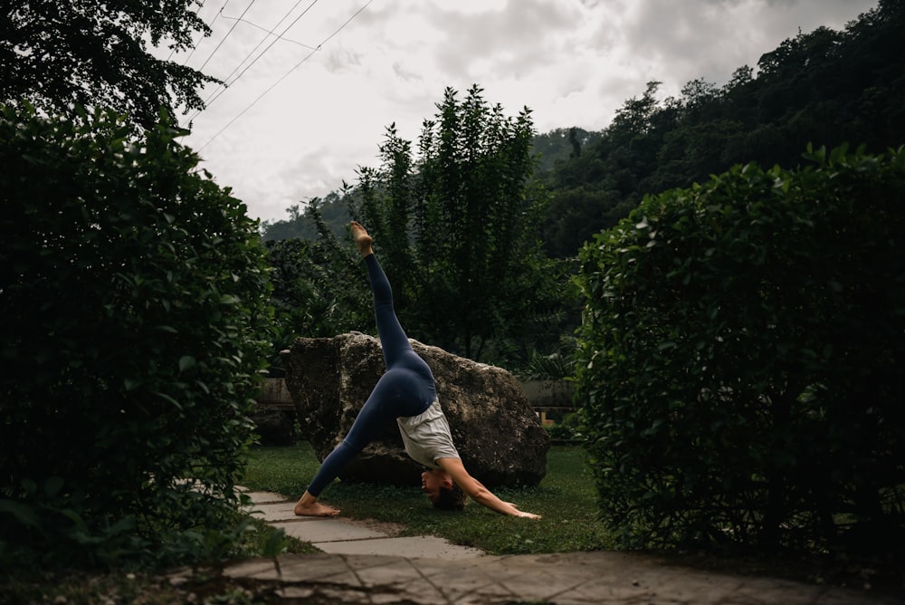 a woman doing a handstand in a park