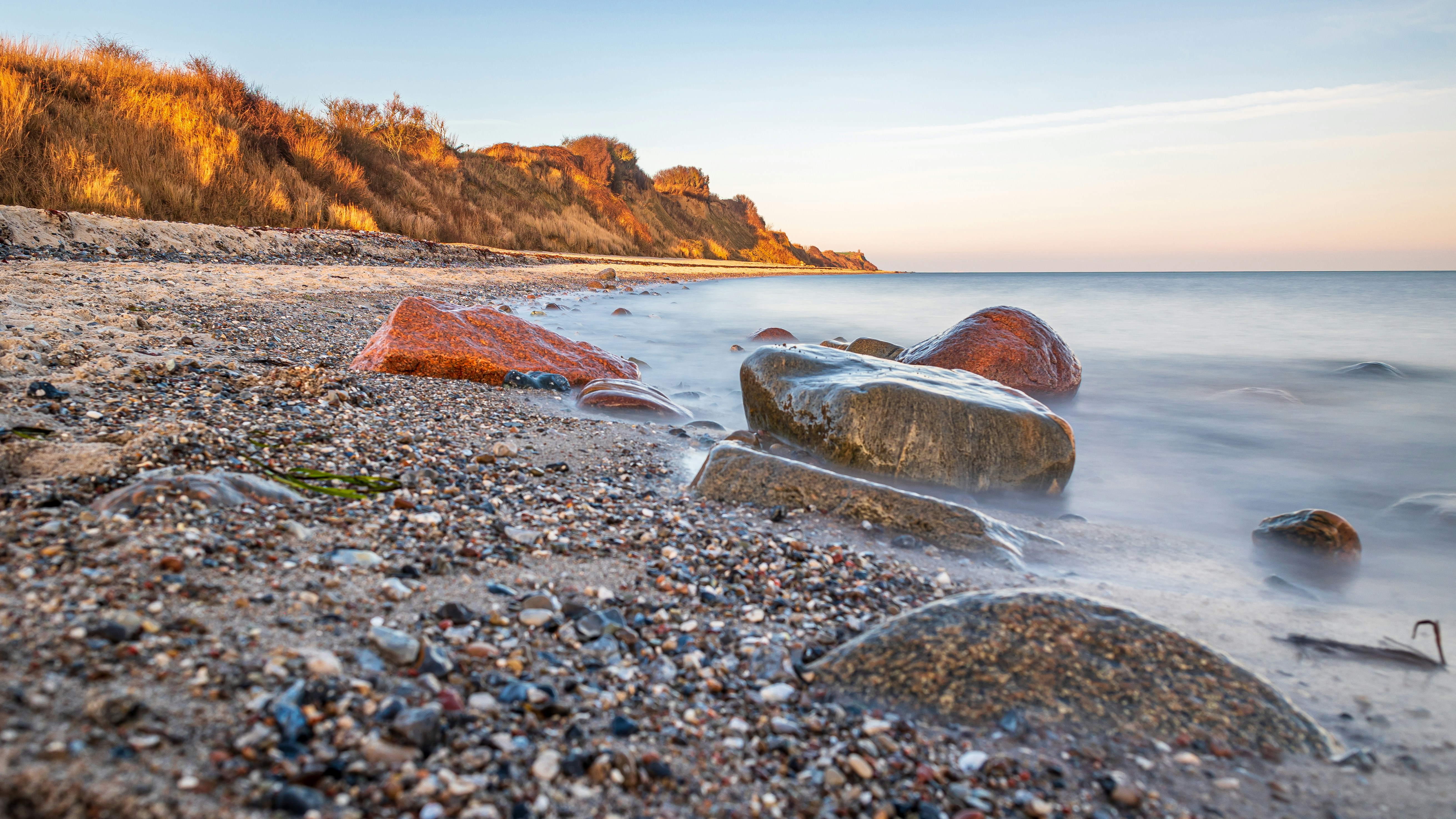 a rocky beach next to a cliff on a sunny day