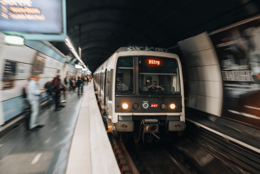 a train traveling through a train station next to a crowd of people