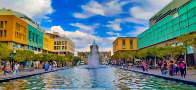 A wide-angle view of a sparkling urban fountain with people enjoying the refreshing atmosphere.