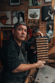 Close-up of a master cigar roller shaping a Bawono cigar with dark brown leaves.