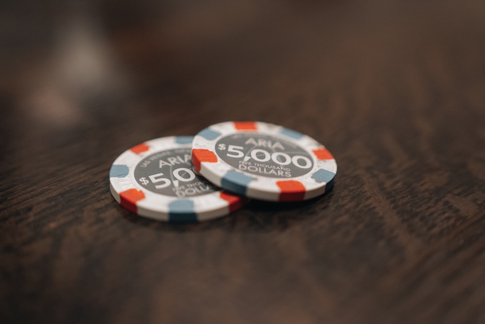 two poker chips sitting on top of a wooden table
