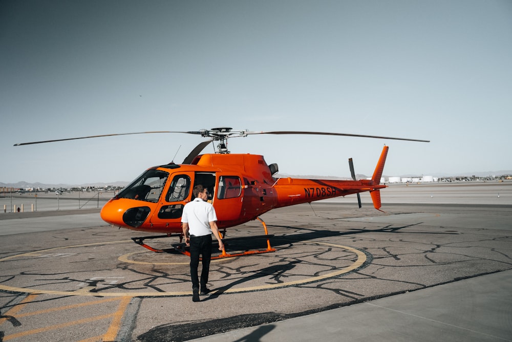 a man standing in front of a helicopter on a runway
