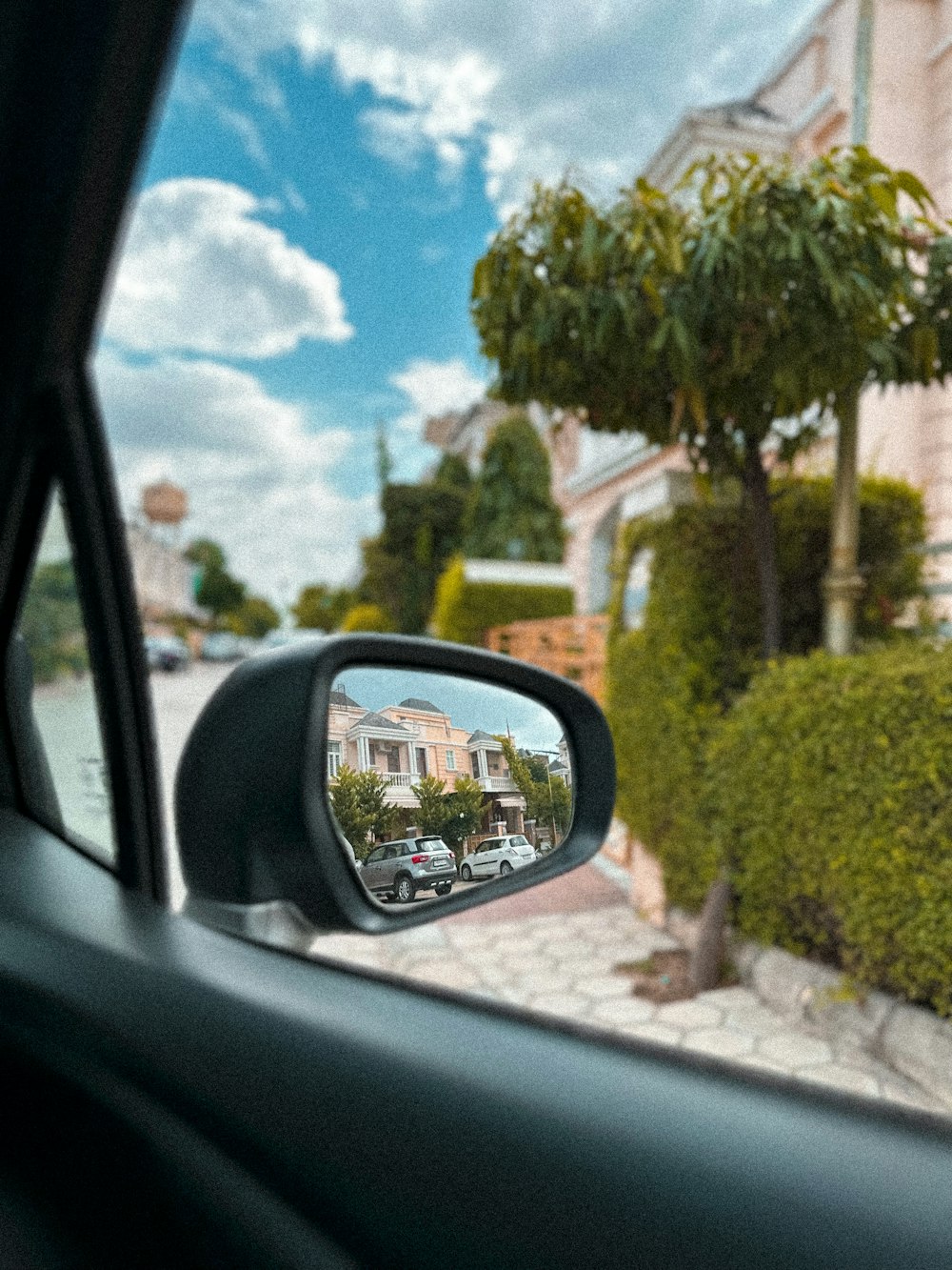 a car's side view mirror with a house in the background