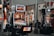 A collection of slot machines is situated inside a building with bright, colorful screens displaying various games and gaming themes. A person is seated nearby, seemingly relaxed with luggage beside them, and the atmosphere is lively with electronic displays.