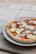 Close-up of a delicious pizza slice with fresh toppings on a rustic wooden table.