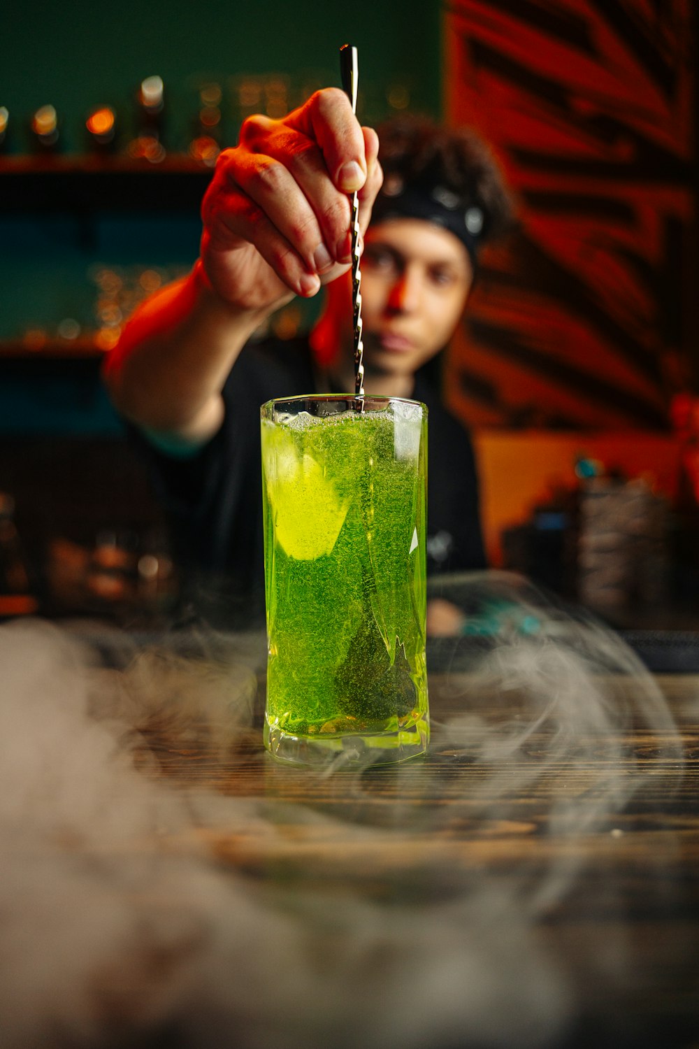 a person is holding a stick above a green drink