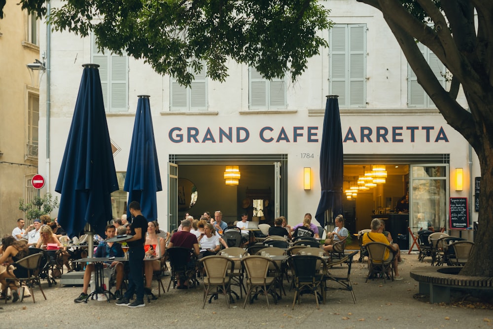 a group of people sitting at tables outside of a restaurant