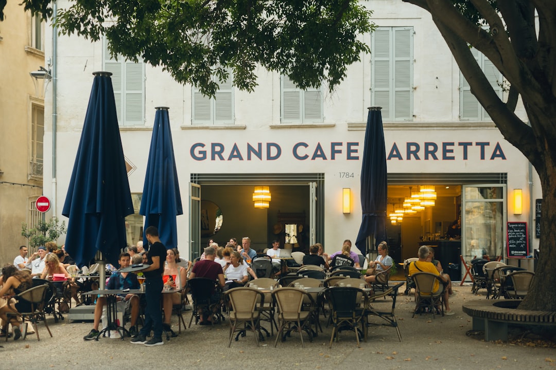 a group of people sitting at tables outside of a restaurant,