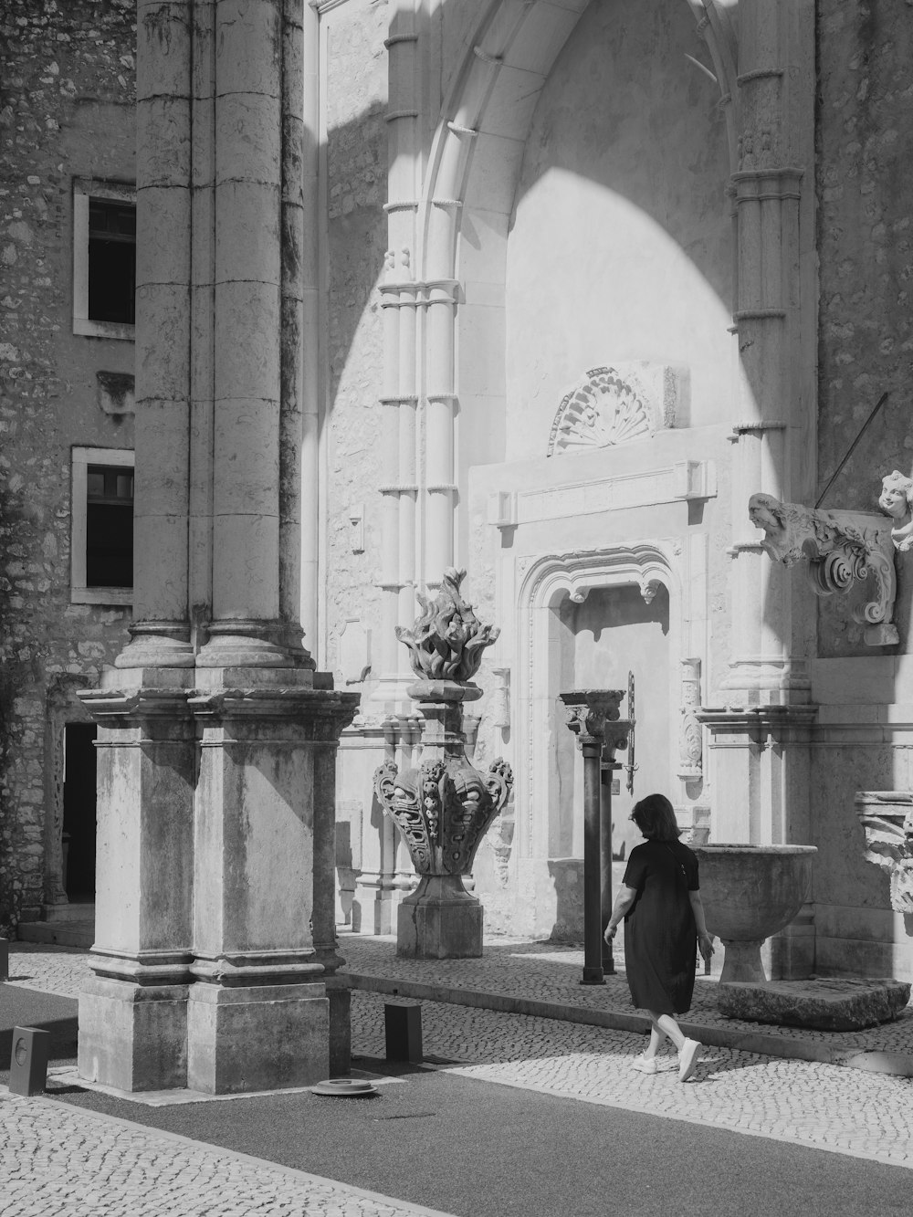 a black and white photo of a woman walking in front of a building