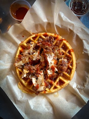 Close-up of a perfectly seasoned chicken breast resting on a warm, buttery waffle.