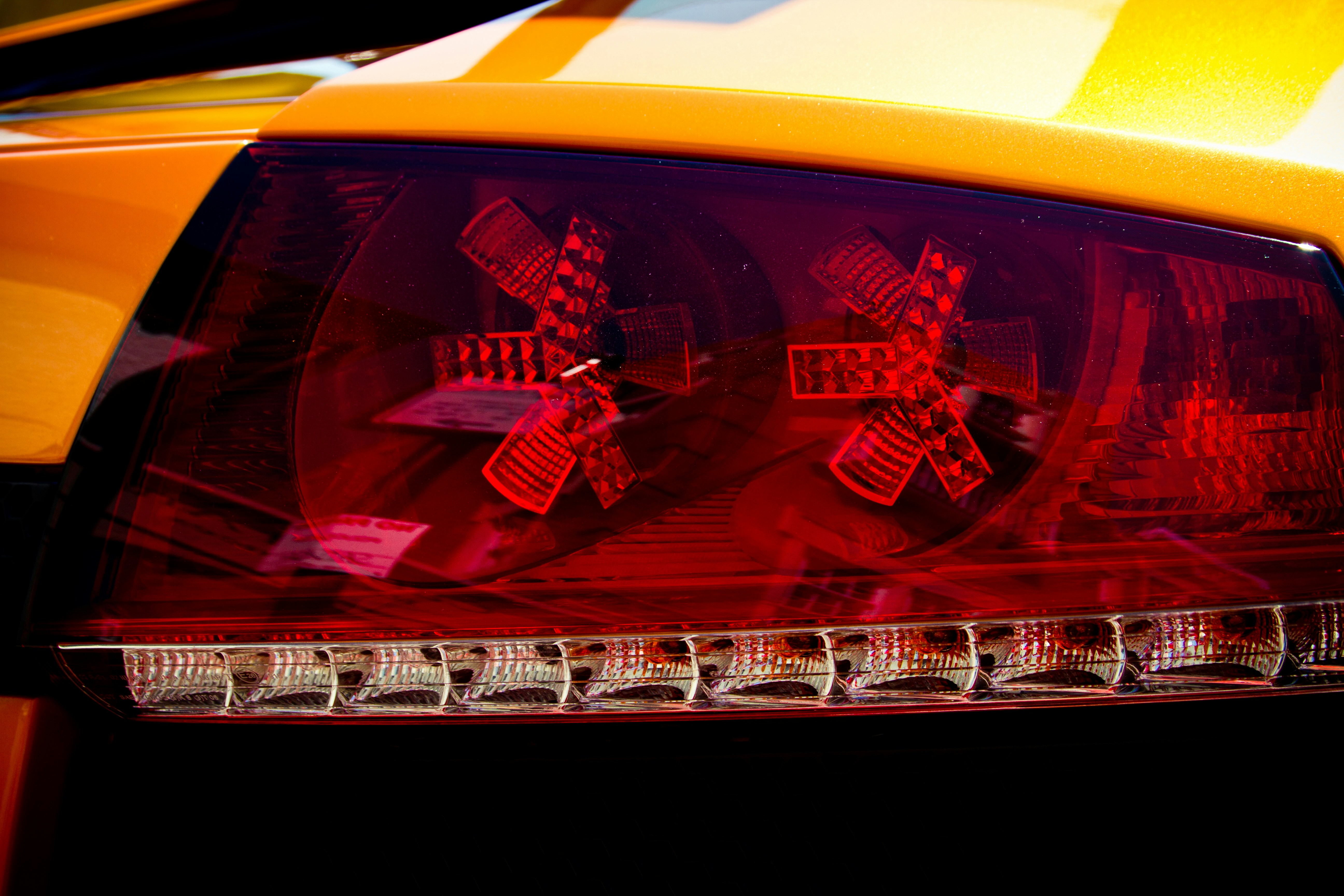 A close up of the tail lights of a yellow sports car photo Free Tail