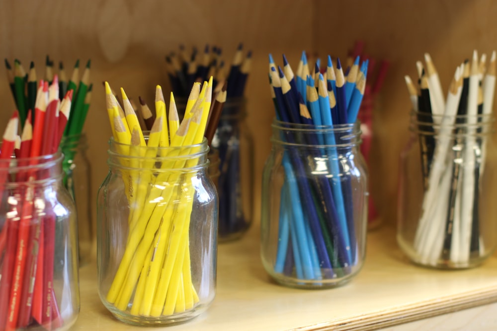 a row of glass jars filled with different colored pencils